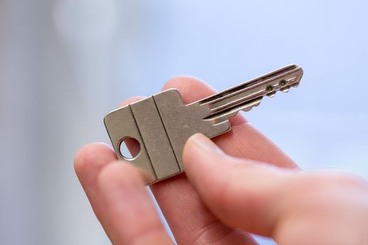 Holding a house key in the hand: New home and property.