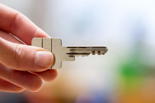 Holding a house key in the hand: New home and property.
