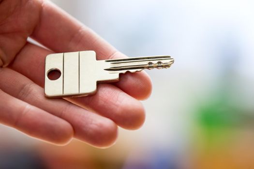 Holding a house key in the hand: New home and property.