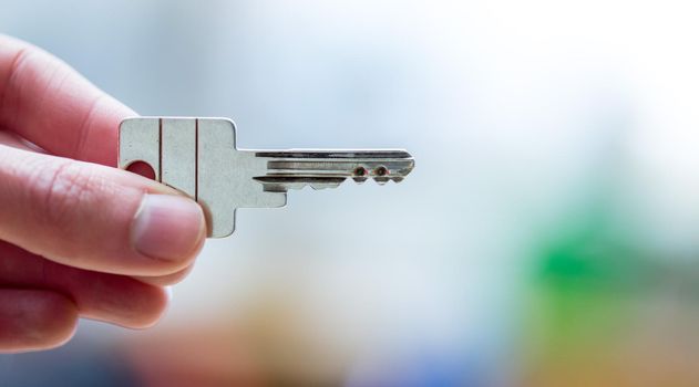 Holding a house key in the hand: New home and property.