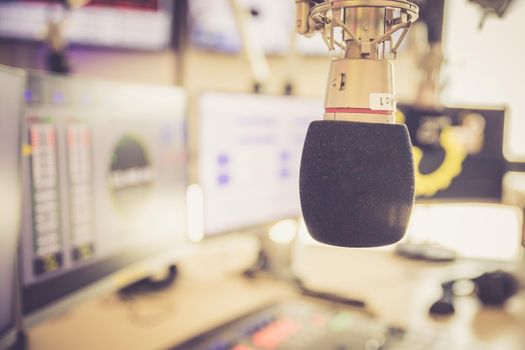 Studio microphone in a broadcasting radio studio, mixer and computer in the blurry background