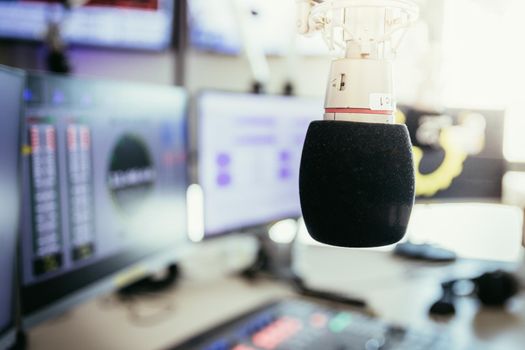 Studio microphone in a broadcasting radio studio, mixer and computer in the blurry background