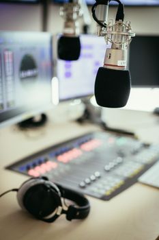 Studio microphone in a broadcasting radio studio, mixer and computer in the blurry background