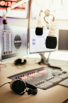 Studio microphone in a broadcasting radio studio, mixer and computer in the blurry background