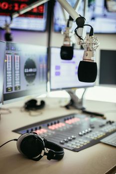 Studio microphone in a broadcasting radio studio, mixer and computer in the blurry background