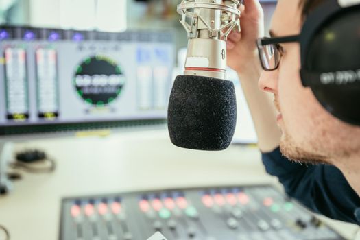 Young man in the broadcasting studio, radio, talking into the microphone