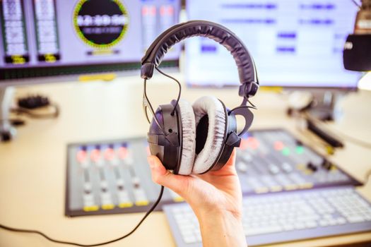 Studio recording: Young is holding headphones in the recording studio, studio in the blurry background