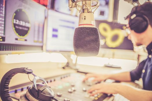 Young man in the broadcasting studio, radio, talking into the microphone