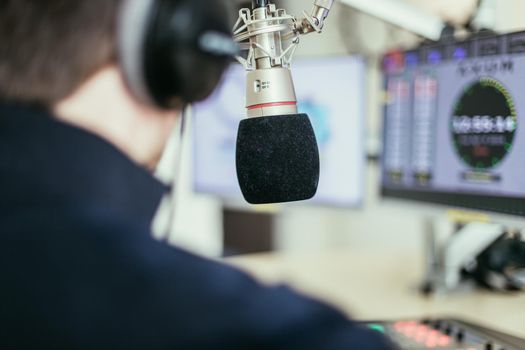 Young man in the broadcasting studio, radio, talking into the microphone