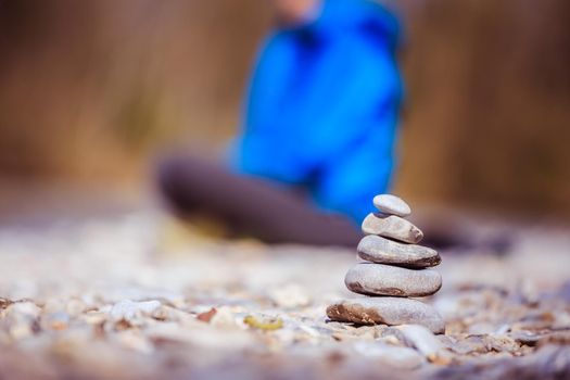 Cairn on a pebble beach, meditating woman in the background