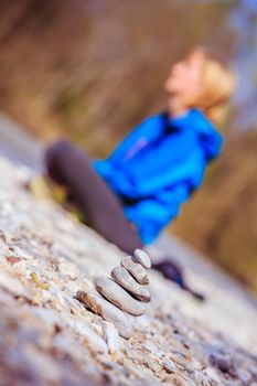 Cairn on a pebble beach, meditating woman in the background