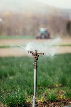 Irrigation plant on an agriculture field, tractor in the background.