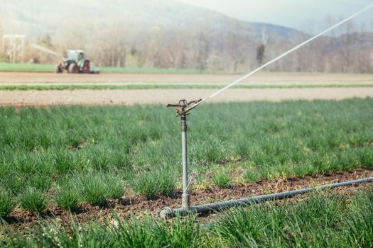 Irrigation plant on an agriculture field, tractor in the background.