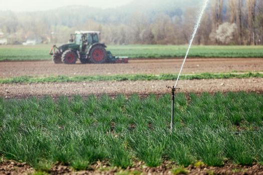 Irrigation plant on an agriculture field, tractor in the background.