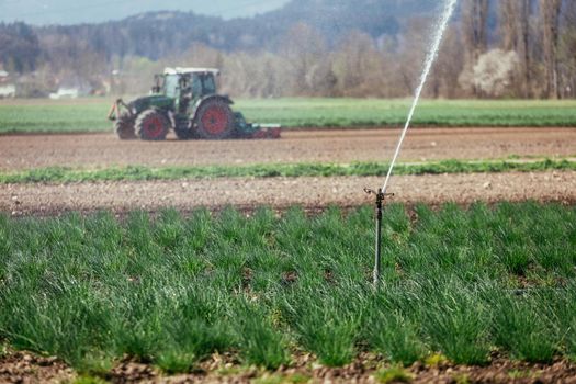 Irrigation plant on an agriculture field, tractor in the background.