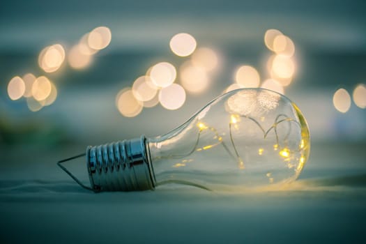 LED light bulb is lying in the bed. Symbol for ideas and innovation. Spot lights in the blurry background.