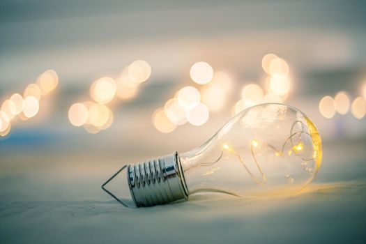 LED light bulb is lying in the bed. Symbol for ideas and innovation. Spot lights in the blurry background.