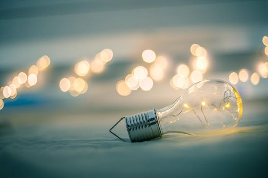 LED light bulb is lying in the bed. Symbol for ideas and innovation. Spot lights in the blurry background.