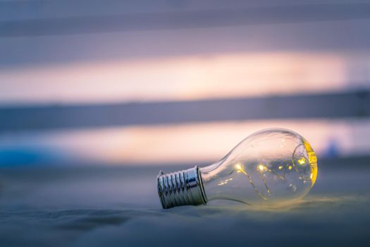 LED light bulb is lying in the bed. Symbol for ideas and innovation. Spot lights in the blurry background.
