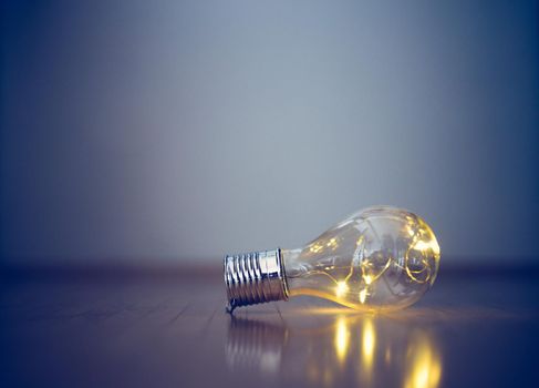 LED light bulb is lying on the wooden floor. Symbol for ideas and innovation. Copy space.