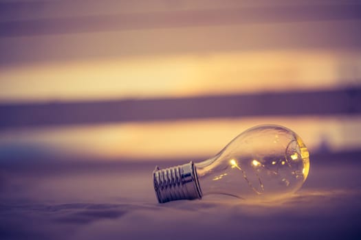 LED light bulb is lying in the bed. Symbol for ideas and innovation. Spot lights in the blurry background.