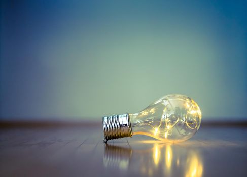 LED light bulb is lying on the wooden floor. Symbol for ideas and innovation. Copy space.
