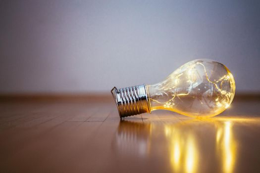 LED light bulb is lying on the wooden floor. Symbol for ideas and innovation. Copy space.
