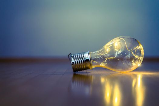 LED light bulb is lying on the wooden floor. Symbol for ideas and innovation. Copy space.