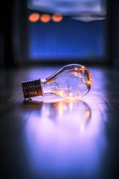 LED light bulb is lying on the wooden floor. Symbol for ideas and innovation. Window and light in the blurry background.