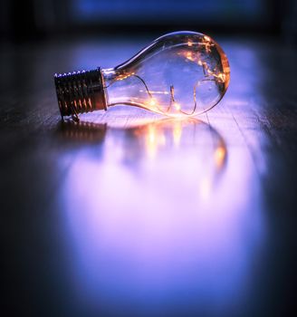 LED light bulb is lying on the wooden floor. Symbol for ideas and innovation. Window and light in the blurry background.