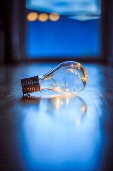 LED light bulb is lying on the wooden floor. Symbol for ideas and innovation. Window and light in the blurry background.