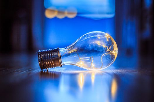 LED light bulb is lying on the wooden floor. Symbol for ideas and innovation. Window and light in the blurry background.