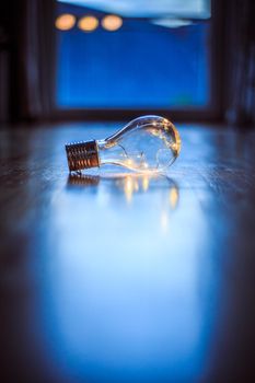 LED light bulb is lying on the wooden floor. Symbol for ideas and innovation. Window and light in the blurry background.