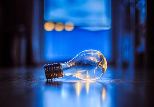 LED light bulb is lying on the wooden floor. Symbol for ideas and innovation. Window and light in the blurry background.