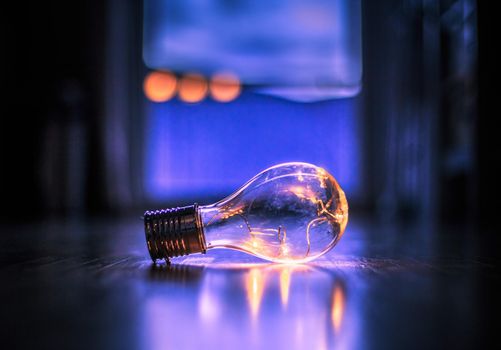LED light bulb is lying on the wooden floor. Symbol for ideas and innovation. Window and light in the blurry background.