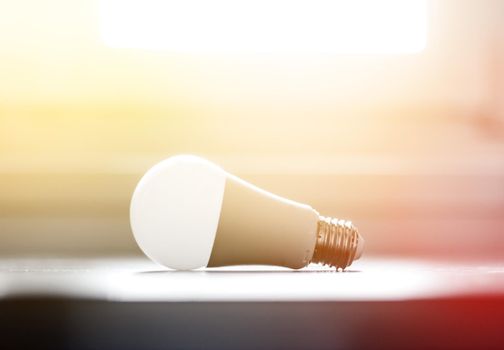 White light bulb lying on a desk, concept for ideas. Sunlight.