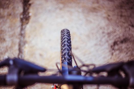 Close up picture of a mountain bike tyre, blurry handlebar, summer day