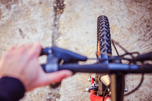 Close up picture of a mountain bike tyre, blurry handlebar, summer day