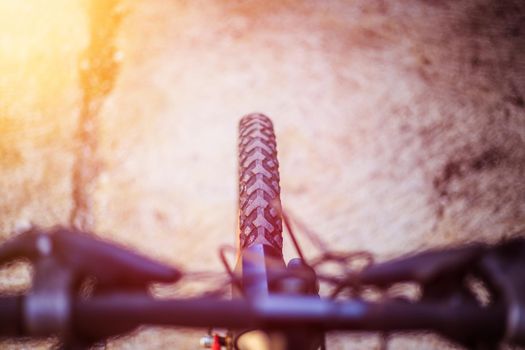 Close up picture of a mountain bike tyre, blurry handlebar, summer day