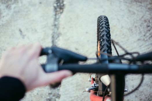 Close up picture of a mountain bike tyre, blurry handlebar, summer day