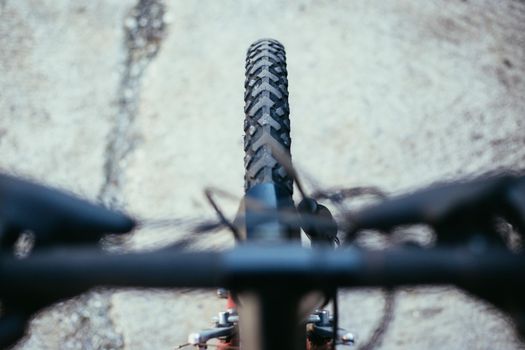 Close up picture of a mountain bike tyre, blurry handlebar, summer day