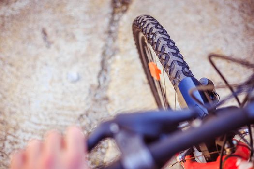 Close up picture of a mountain bike tyre, blurry handlebar, summer day
