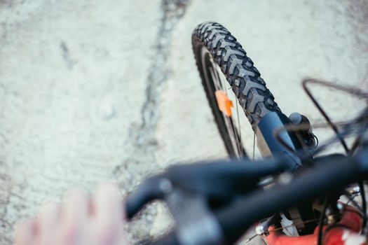 Close up picture of a mountain bike tyre, blurry handlebar, summer day