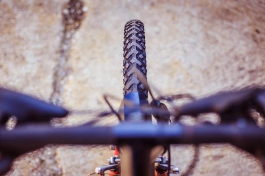 Close up picture of a mountain bike tyre, blurry handlebar, summer day
