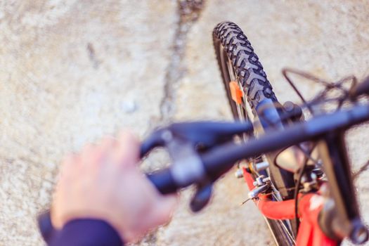 Close up picture of a mountain bike tyre, blurry handlebar, summer day