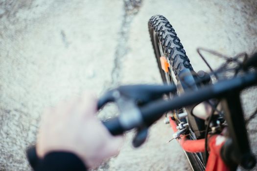 Close up picture of a mountain bike tyre, blurry handlebar, summer day