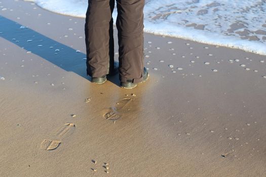 Human feet in black shoes at a baltic sea beach in northern Germany