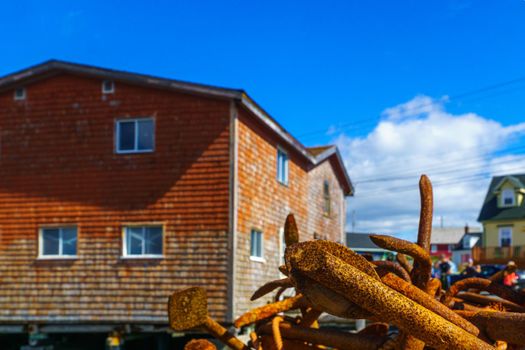 View of rusty anchors, and colorful houses, in the fishing village Peggys Cove, Nova Scotia, Canada