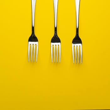 three forks arranged on a yellow surface