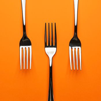 three forks arranged on an orange surface